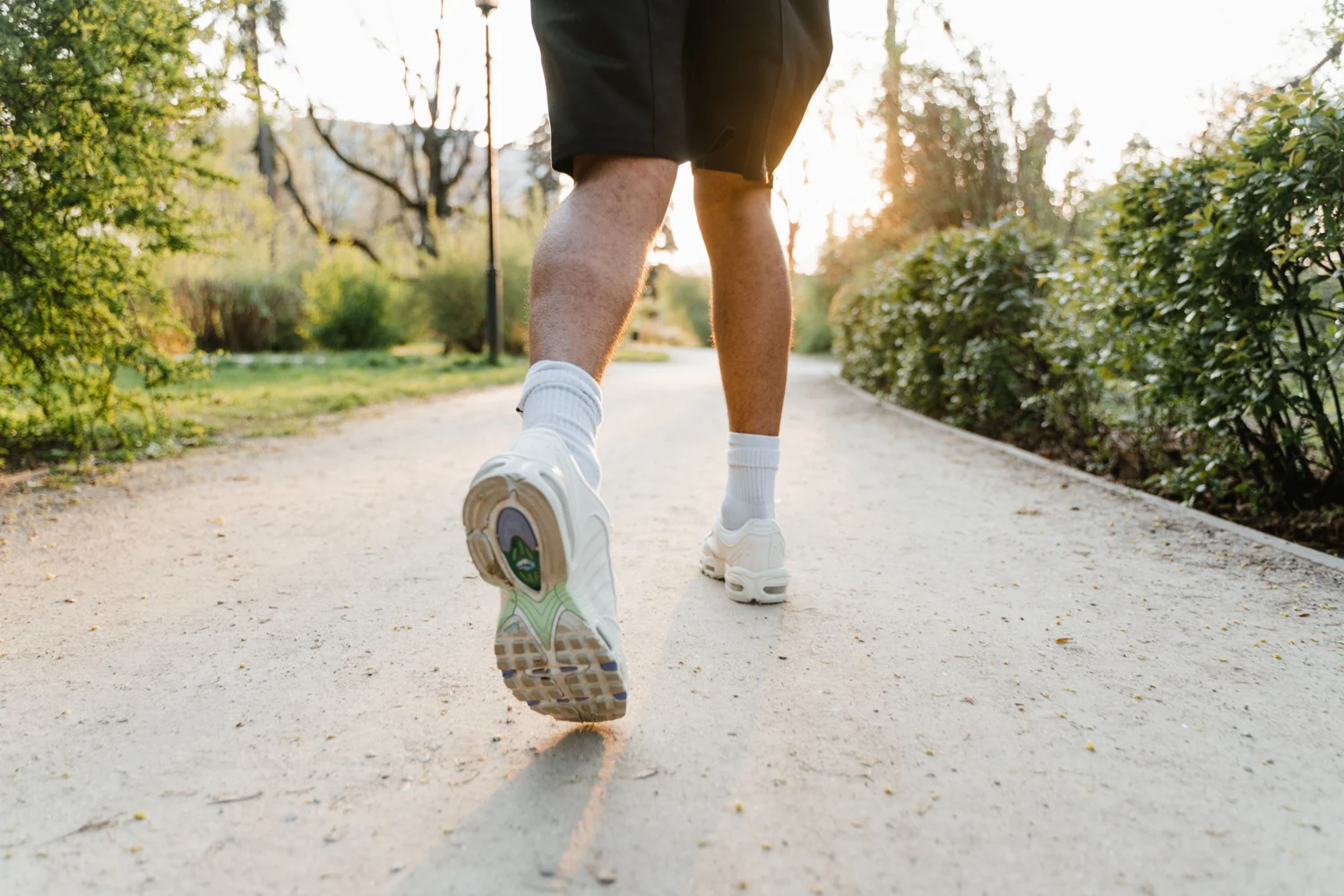 Laufschuhe und Beine einer laufenden Person auf einem Parkweg