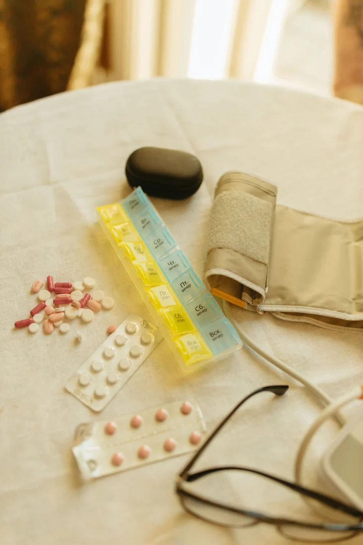 Medikamente, Dosierbox und Blutdruckmessgerät auf einem Tisch