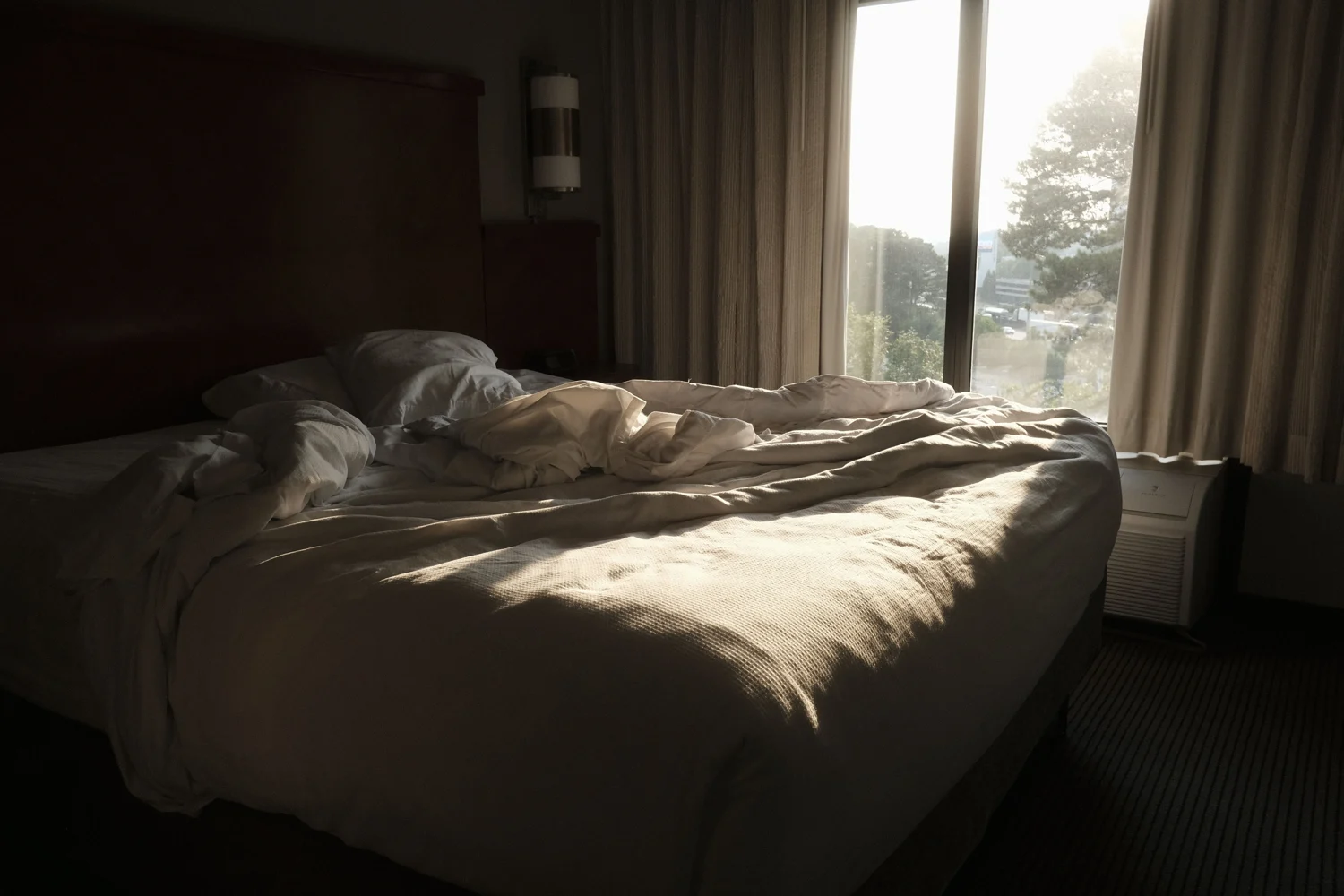 Bett und Fenster in einem Schlafzimmer im Morgenlicht